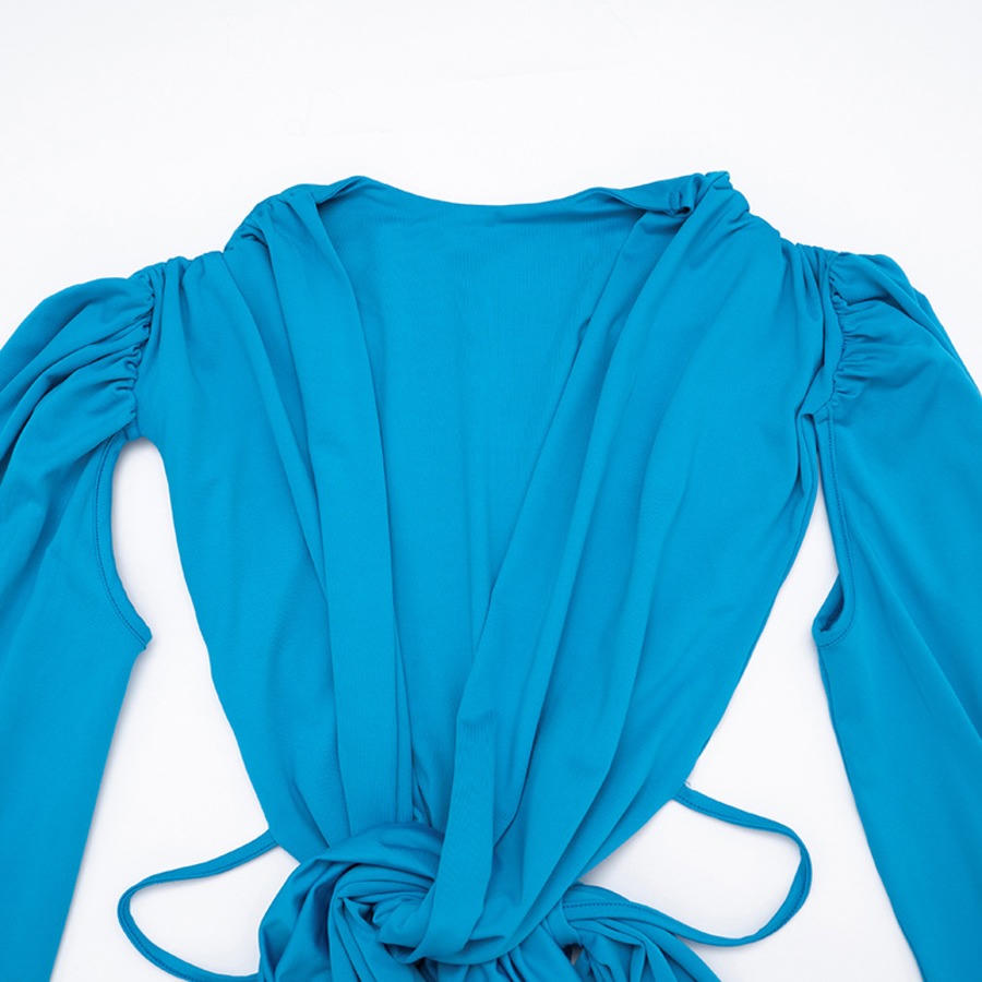 Close-up of the turquoise dress showing its ruched fabric and draped front.