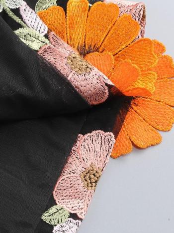 Close-up of embroidered flowers on a garment with a neutral background