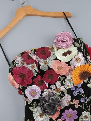 Black mini dress with colorful floral embroidery on a hanger against a gray background