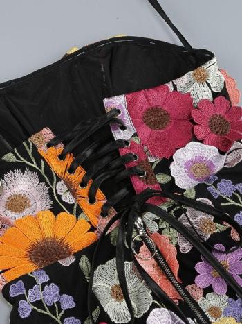 Black bag with colorful floral embroidery on a gray background