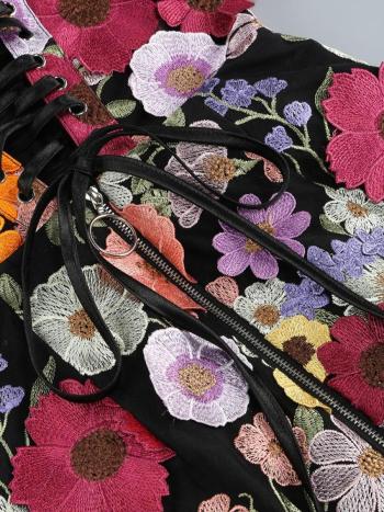 Close-up of a black bag with colorful floral embroidery on a gray background