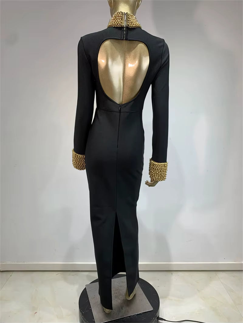 Black dress with gold embellishments on a mannequin against a plain background