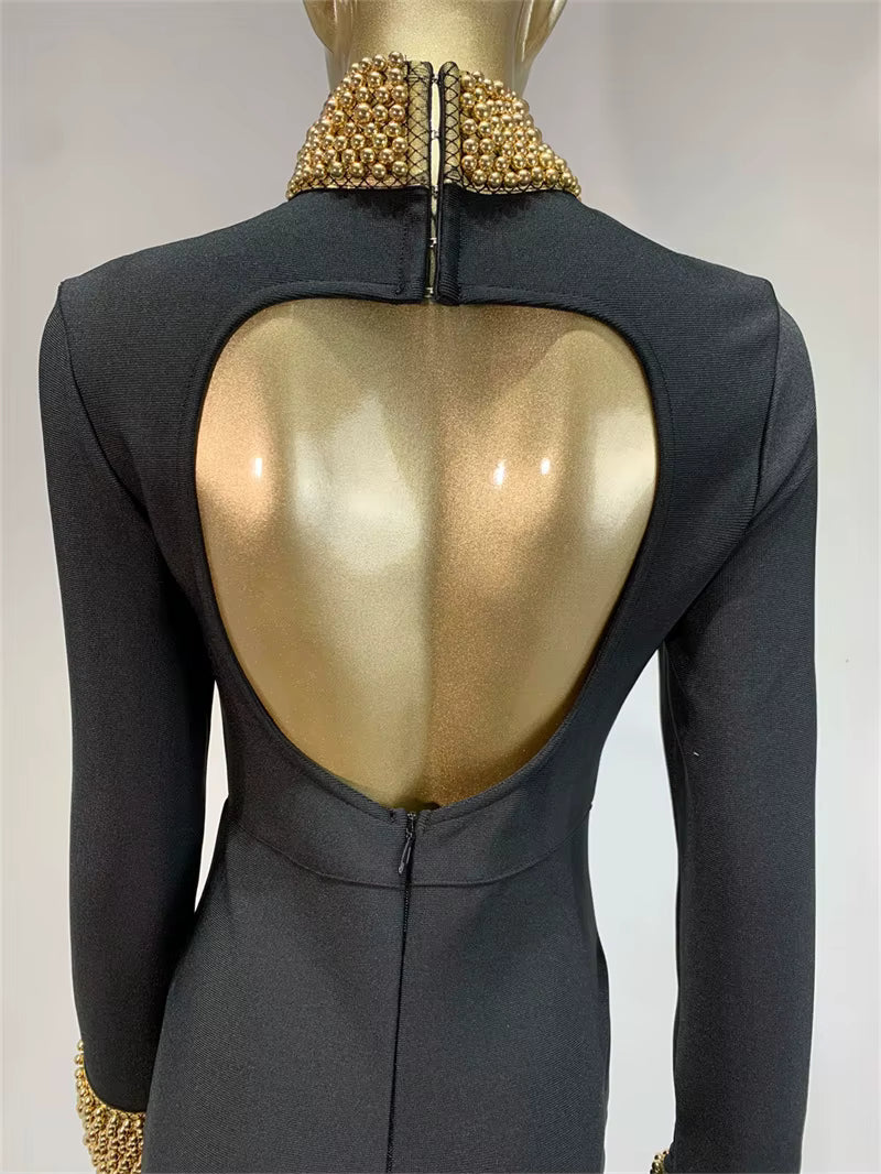 Mannequin wearing a black dress with a gold open-back design on a plain background