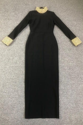 Black dress with gold embellishments on sleeves and neckline on a gray surface