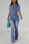 A woman wearing a blue denim jumpsuit with short sleeves, a turn-down collar, and cargo pockets, paired with ankle boots and carrying a green purse.