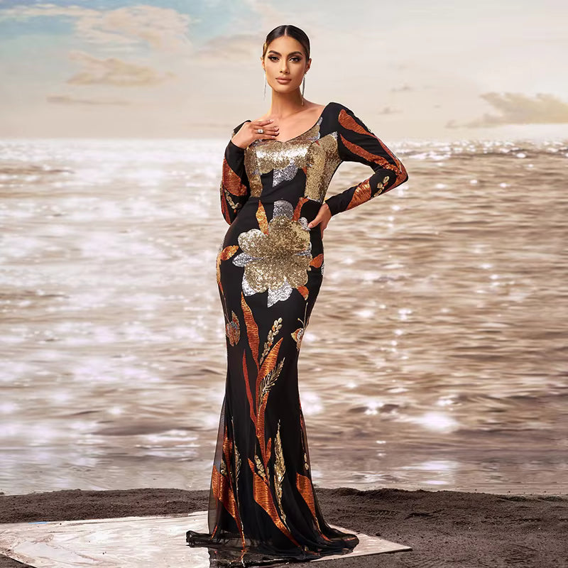 Woman in a patterned dress standing on a beach with water in the background