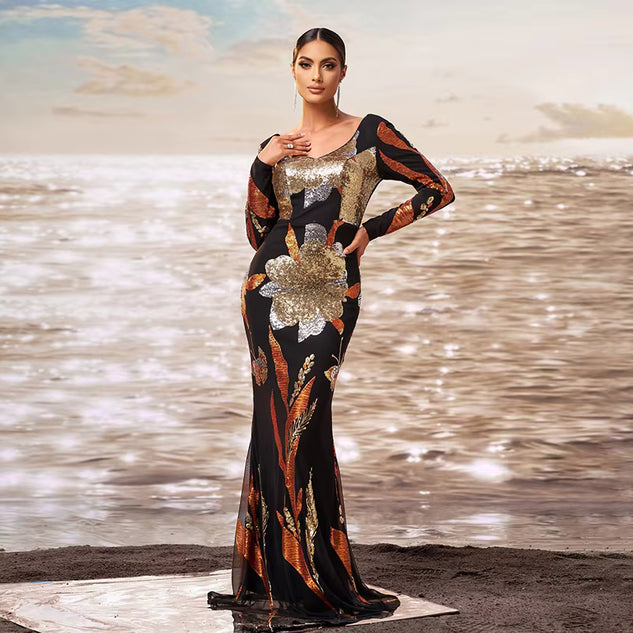 Woman in a patterned dress standing on a beach with water in the background